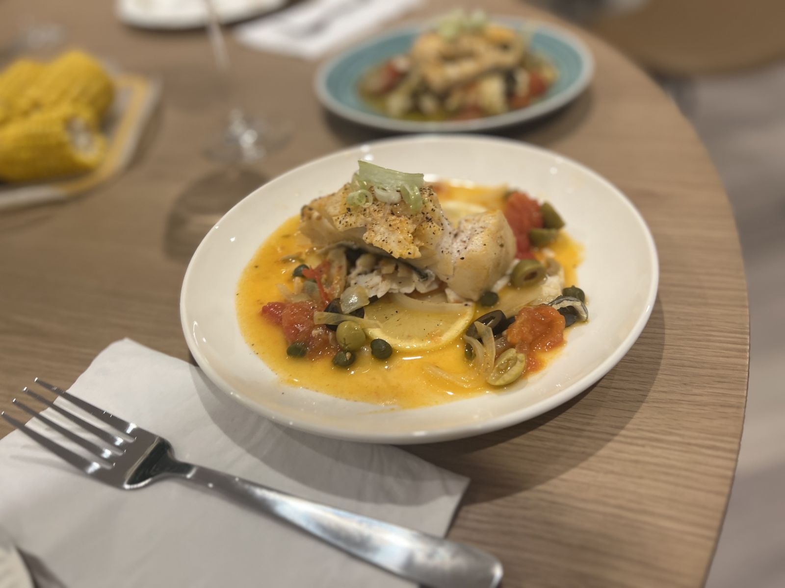 Pan-fried cod with olives, capers, tomato and a lemony broth